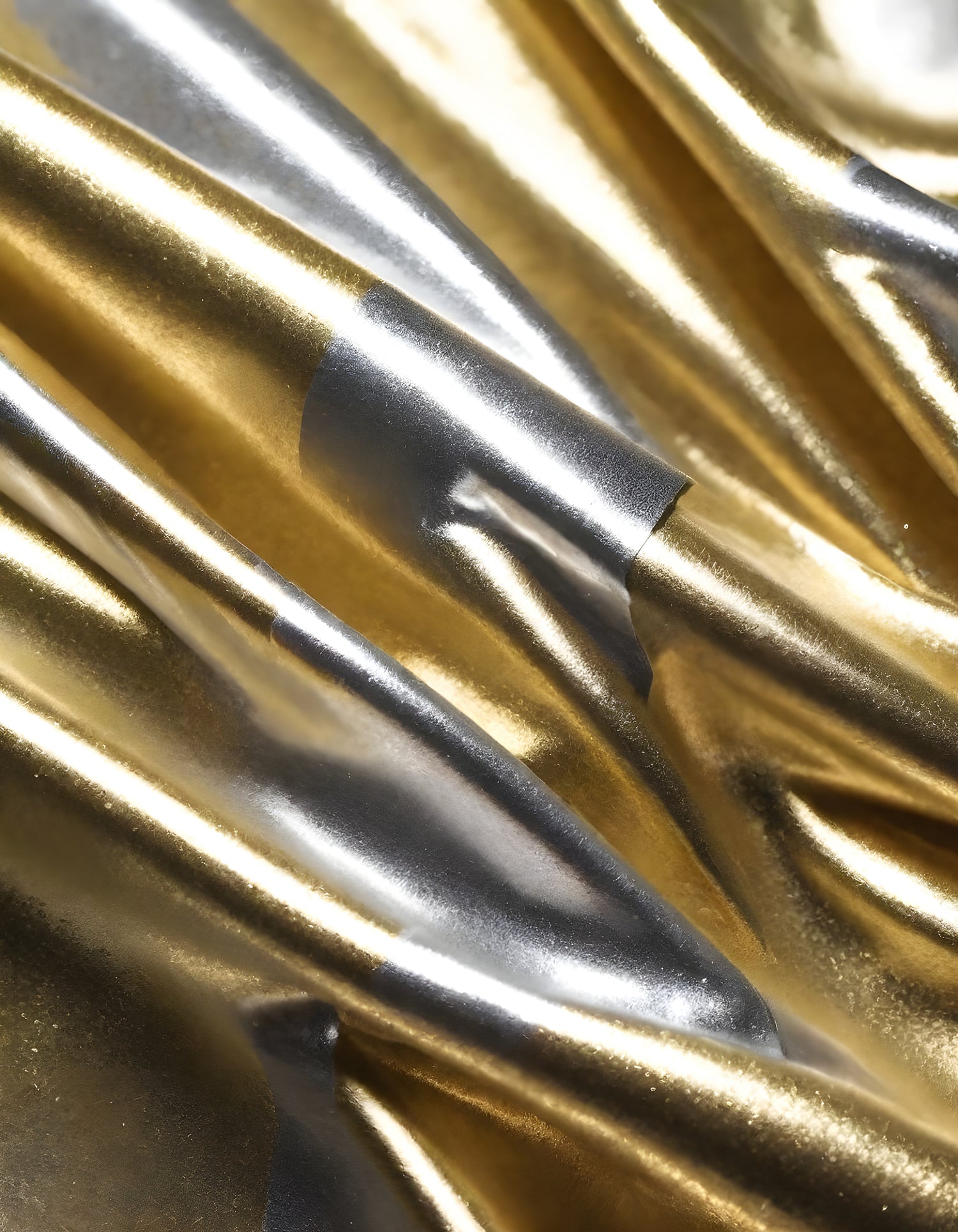 Metallic golden and silver fabric creates elegant textures with intricate folds and reflections under soft lighting