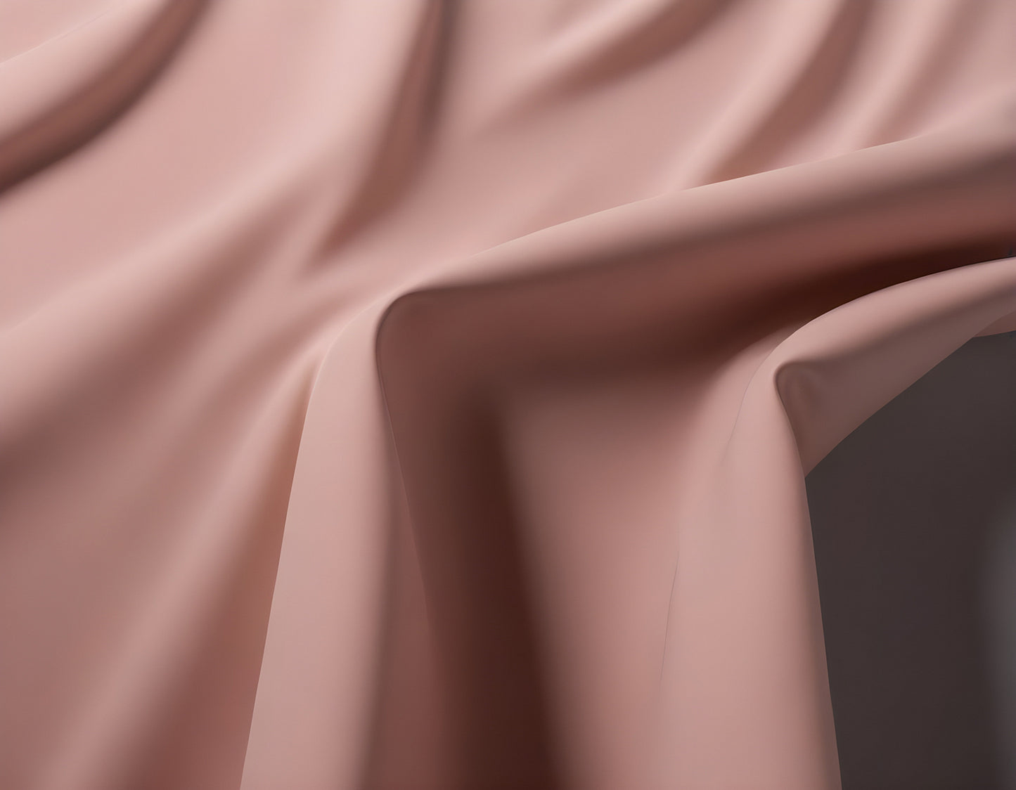 Elegant draped fabric in soft pink resting on a textured surface captured in soft natural light