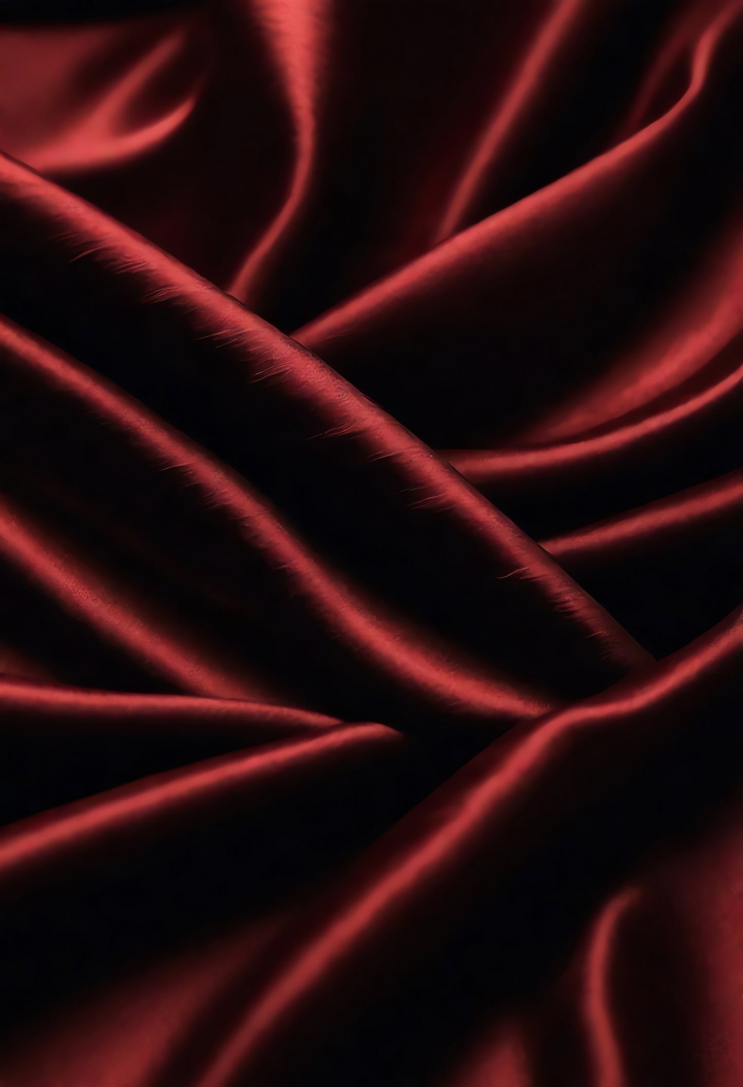 Elegant deep red satin fabric drapes gracefully, highlighting rich texture and luxurious sheen in soft lighting