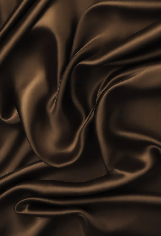 Luxurious dark brown satin fabric draped elegantly creating soft waves and folds, ideal for fashion or interior design projects