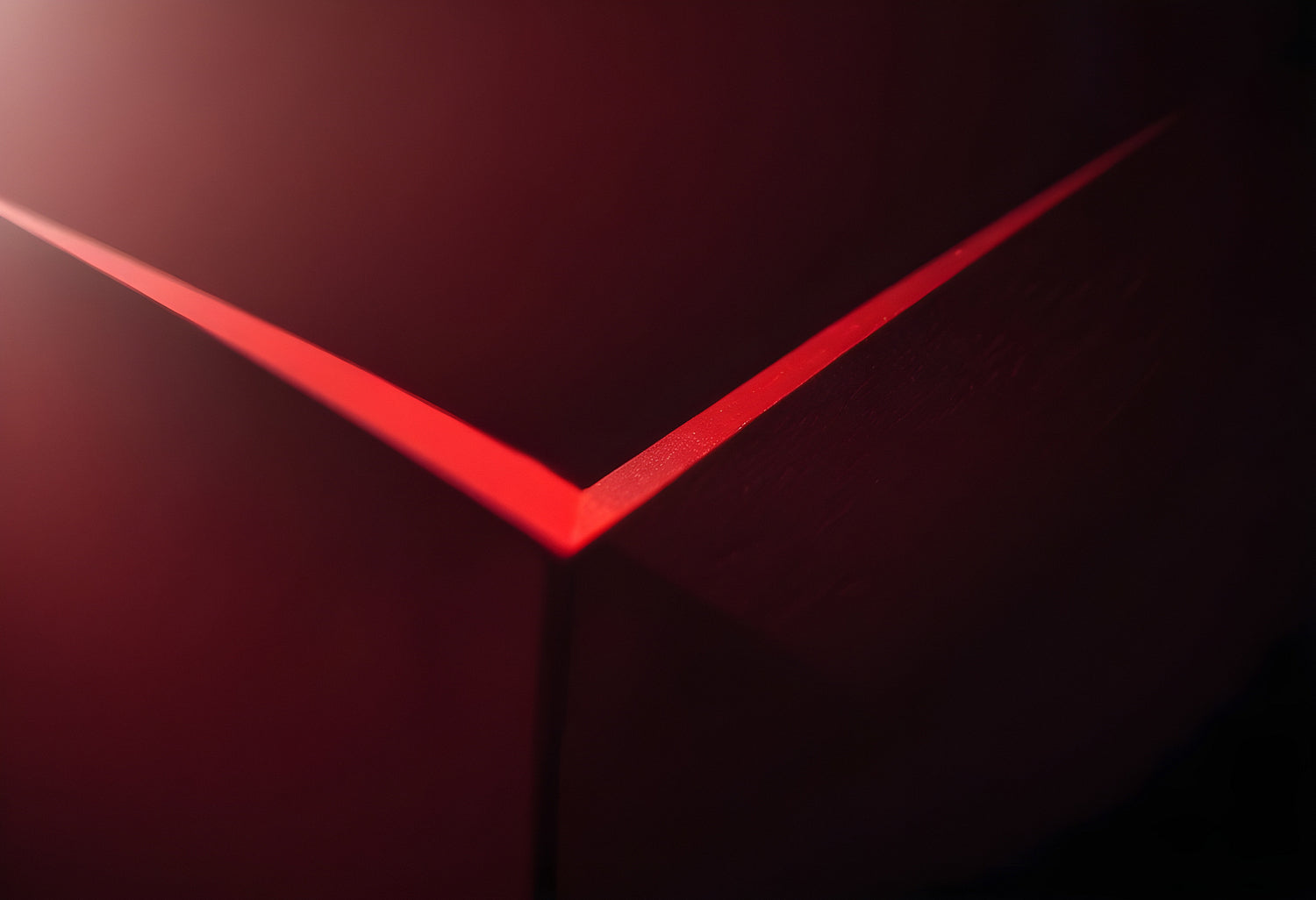 A close-up view of a red geometric shape against a dark background showcasing light reflections and angular lines