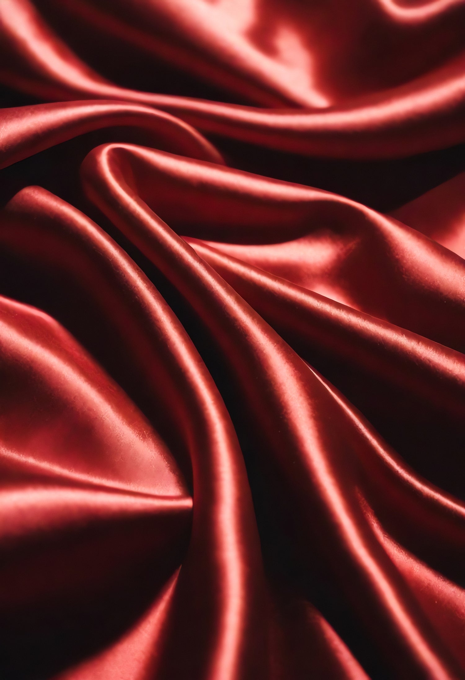 Luxurious red satin fabric with gentle folds captured in soft light