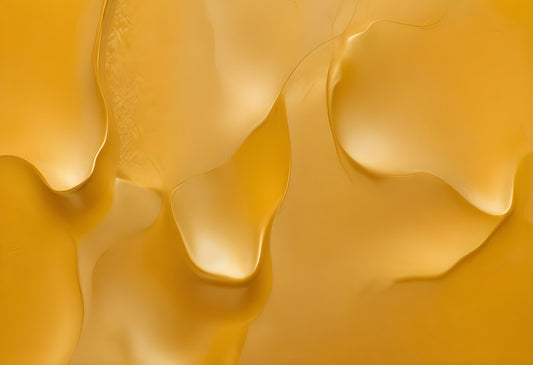 Abstract yellow liquid textures showcasing smooth curves and glossy reflections in natural light