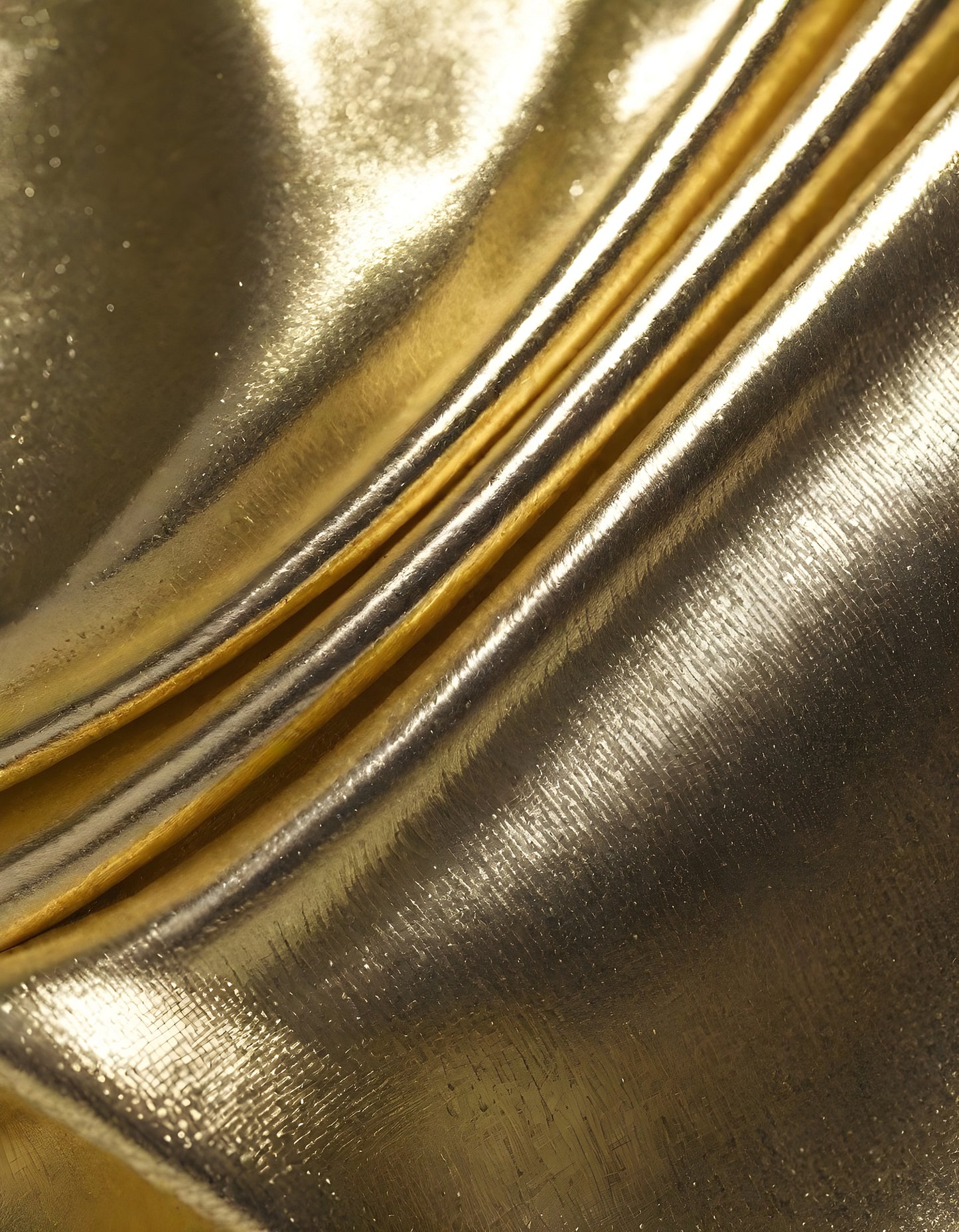 Metallic golden and silver fabric creates elegant textures with intricate folds and reflections under soft lighting