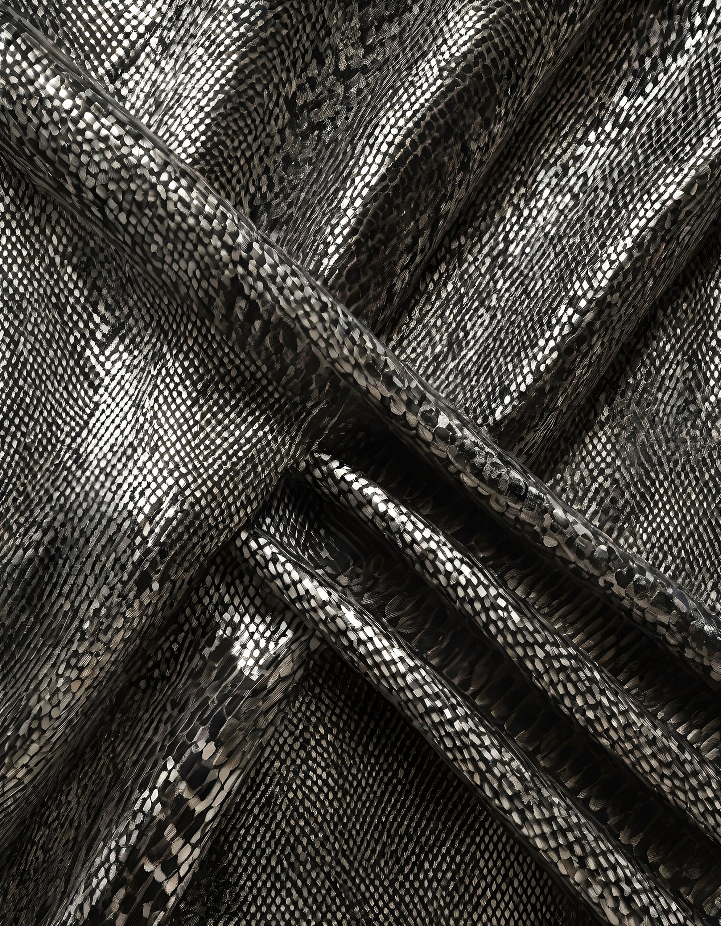 Shimmering black snake print fabric displayed in folds