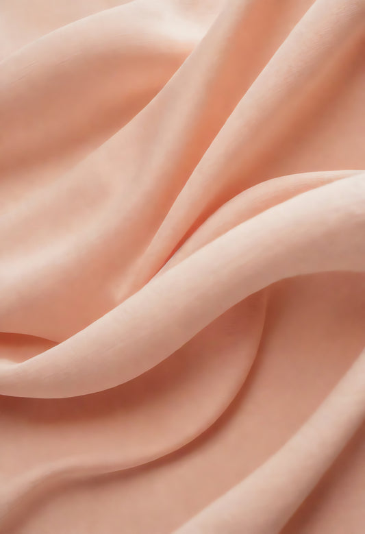 Soft peach fabric draped elegantly on a neutral background during daylight