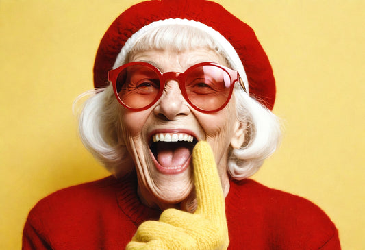 Joyful elderly woman in bright outfit and oversized glasses smiling playfully against a vibrant yellow background