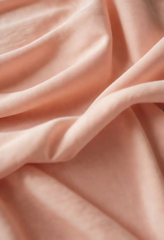 Soft peach fabric draped elegantly on a neutral background during daylight