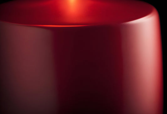 A close-up of a vibrant red object reflecting light in a minimalist setting, showcasing textural details and color depth