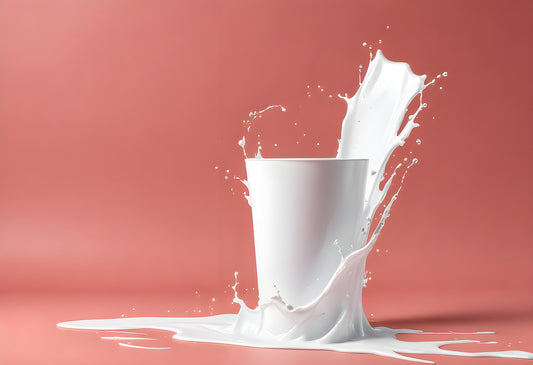 Milk splashes dramatically from a white cup onto a colorful background in a creative kitchen setting