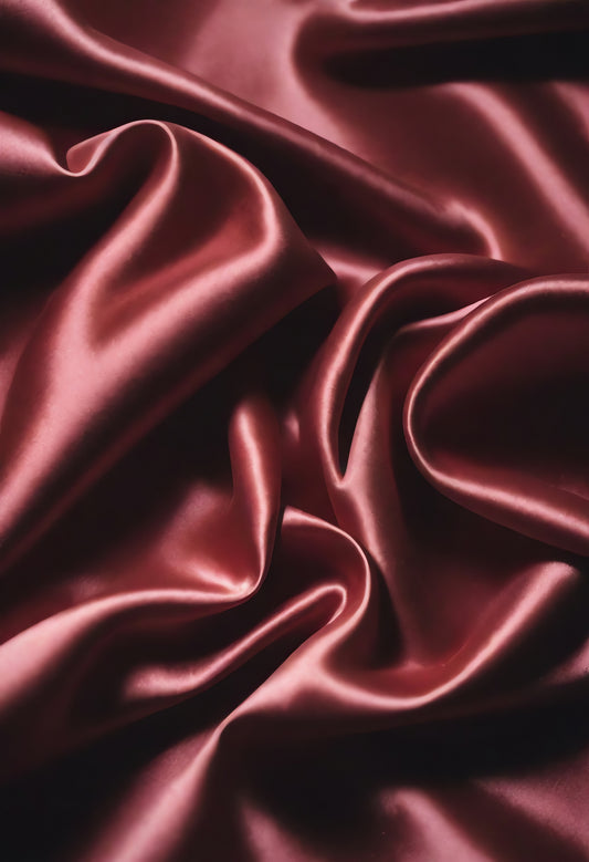 Luxurious burgundy silk fabric draped elegantly, capturing soft folds and rich texture in natural light