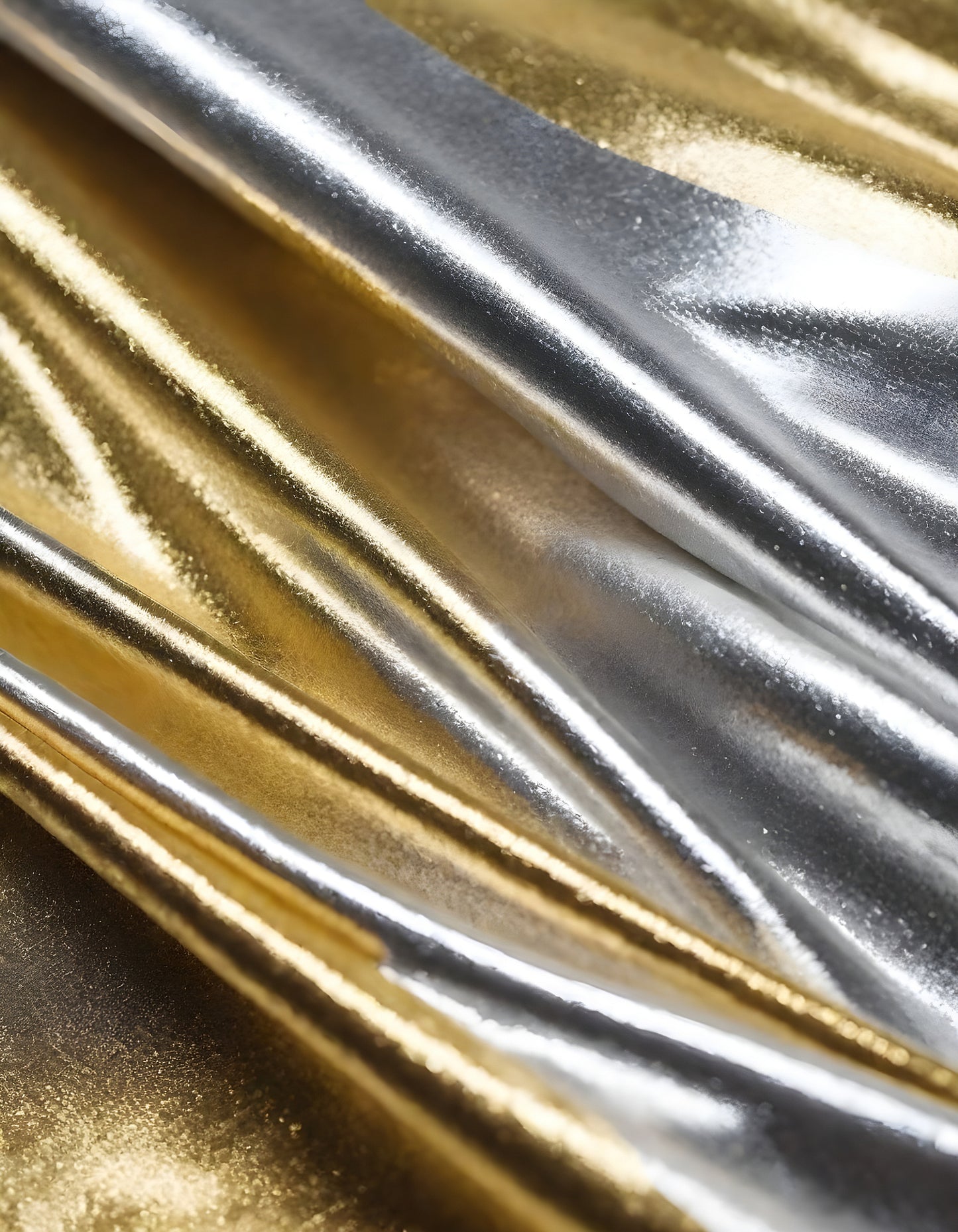 Metallic golden and silver fabric creates elegant textures with intricate folds and reflections under soft lighting