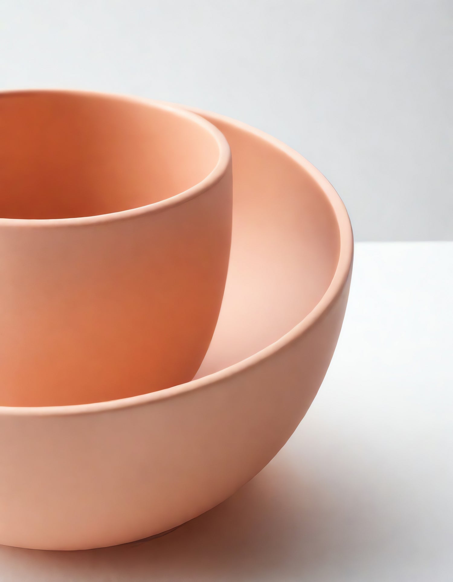 Three nested bowls in soft coral tones on a light background showcasing modern minimalist design and craftsmanship