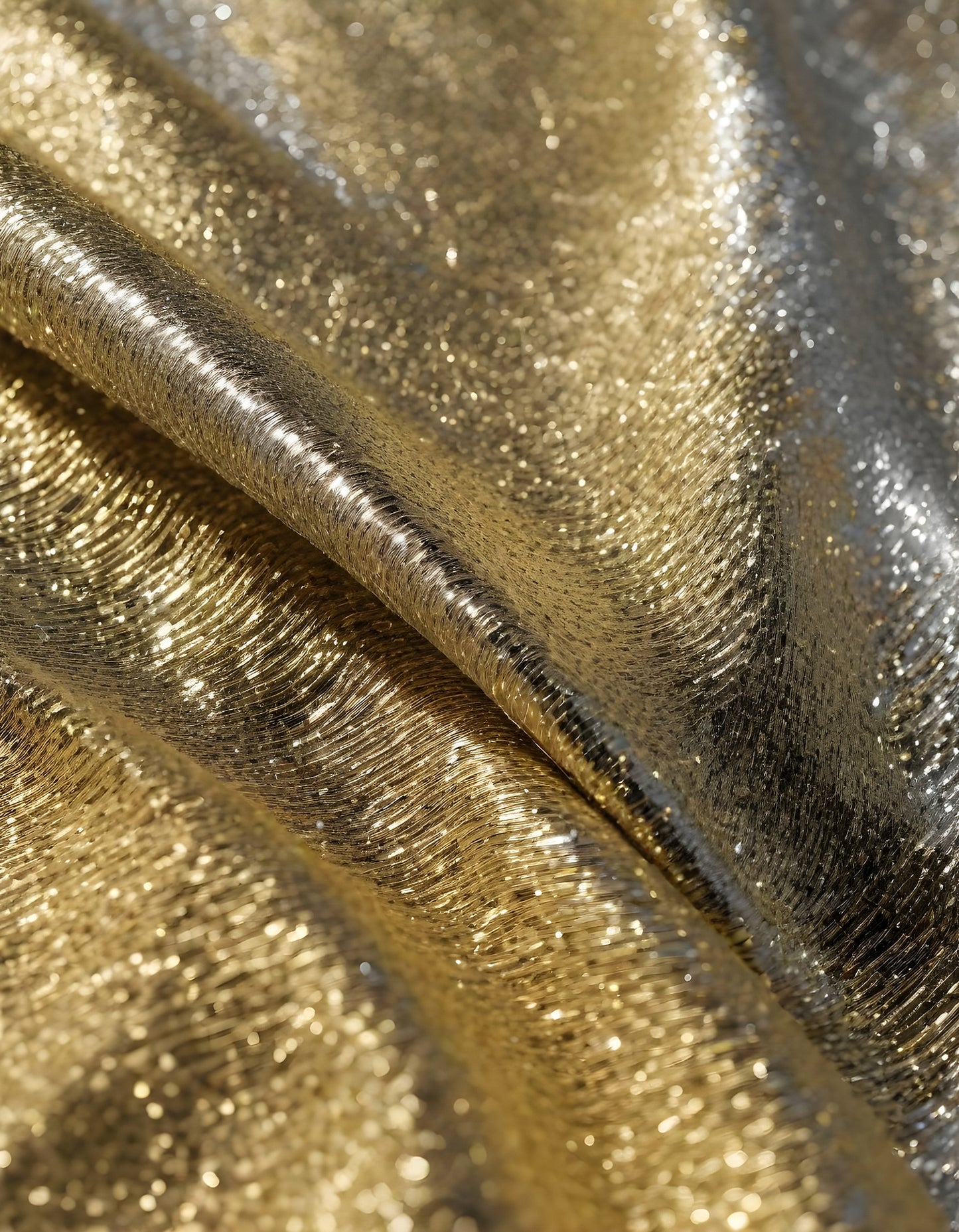 Metallic golden and silver fabric creates elegant textures with intricate folds and reflections under soft lighting