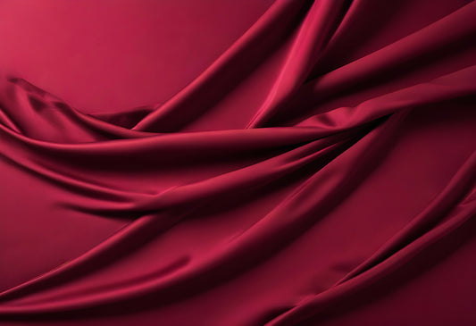 Red satin fabric draped elegantly on a surface with soft folds and shadows