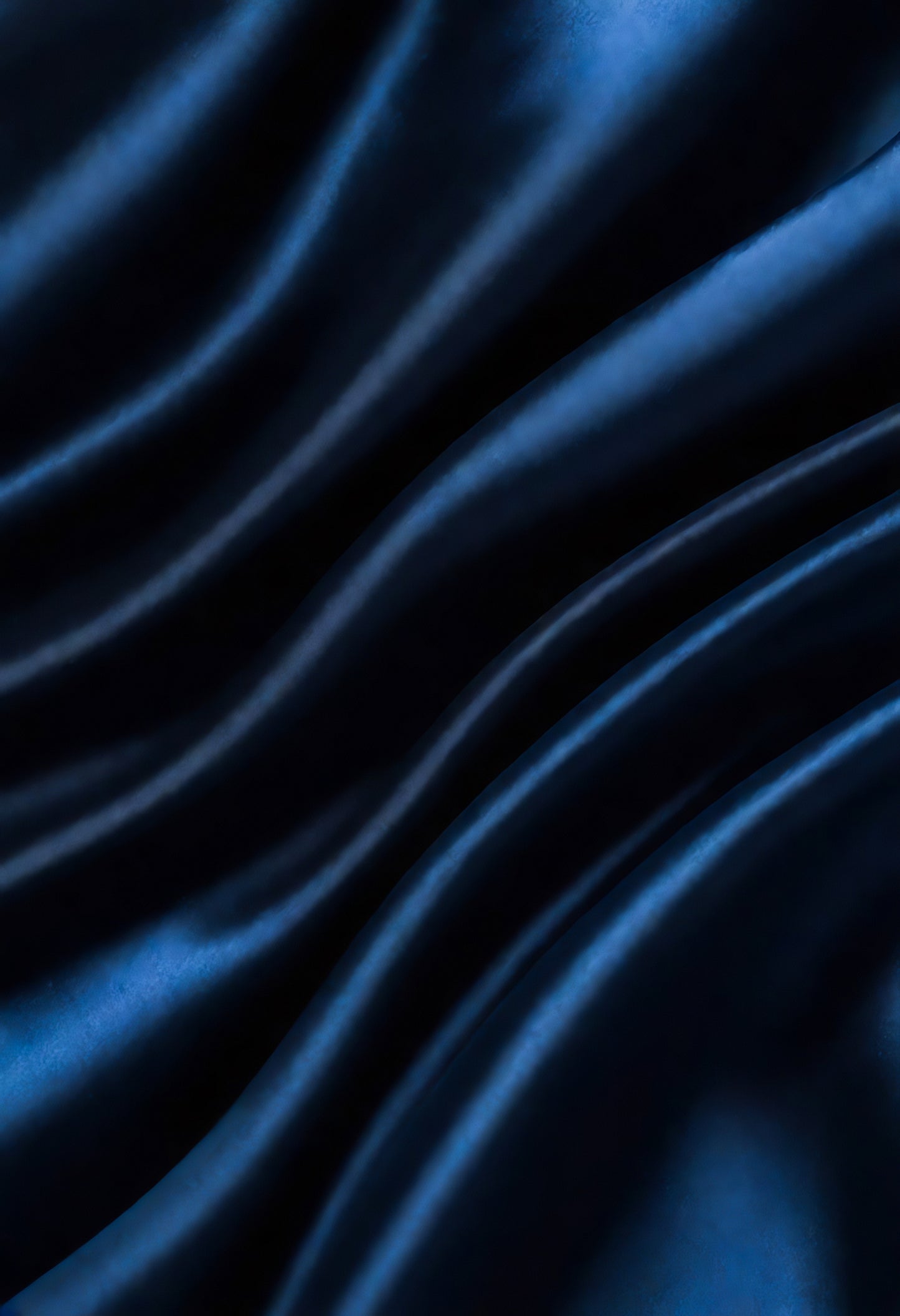 A close-up view of elegant dark blue fabric displaying smooth waves and rich textures in natural light