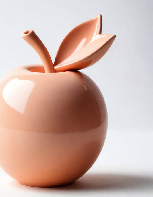 Ceramic vase shaped like a peach apple with a leaf, showcasing a modern design and smooth texture on a plain background