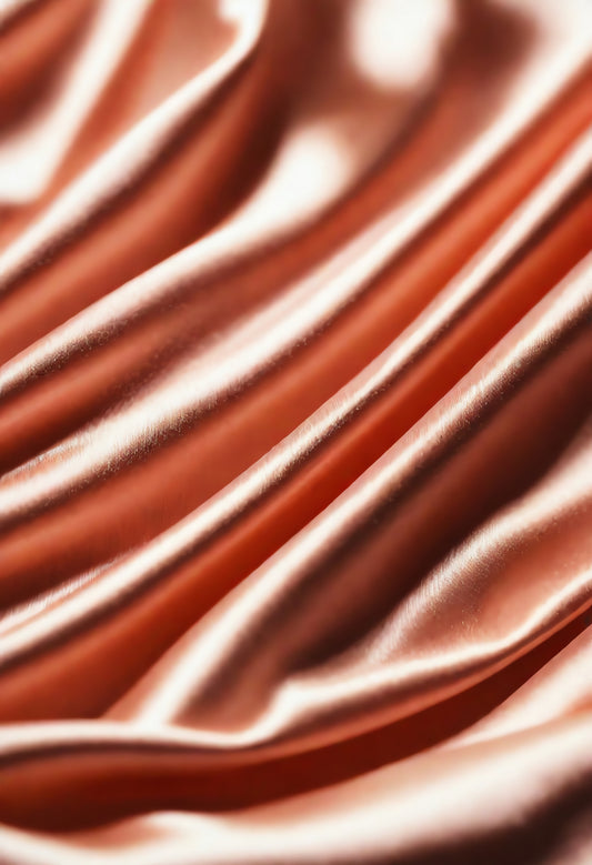 Soft pink satin fabric draping on a surface, showcasing smooth texture and elegant folds