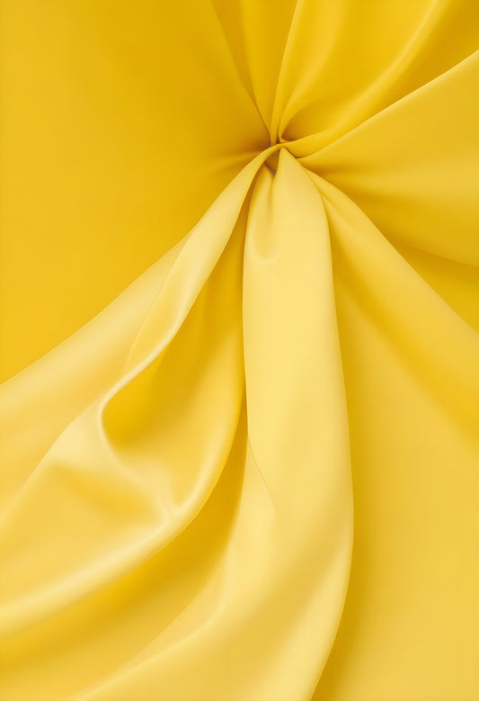 Soft yellow fabric draped elegantly on a flat surface, showcasing smooth textures and rich color