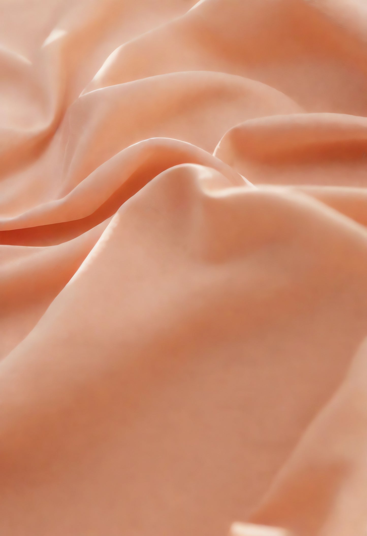 Soft peach fabric draped elegantly on a neutral background during daylight