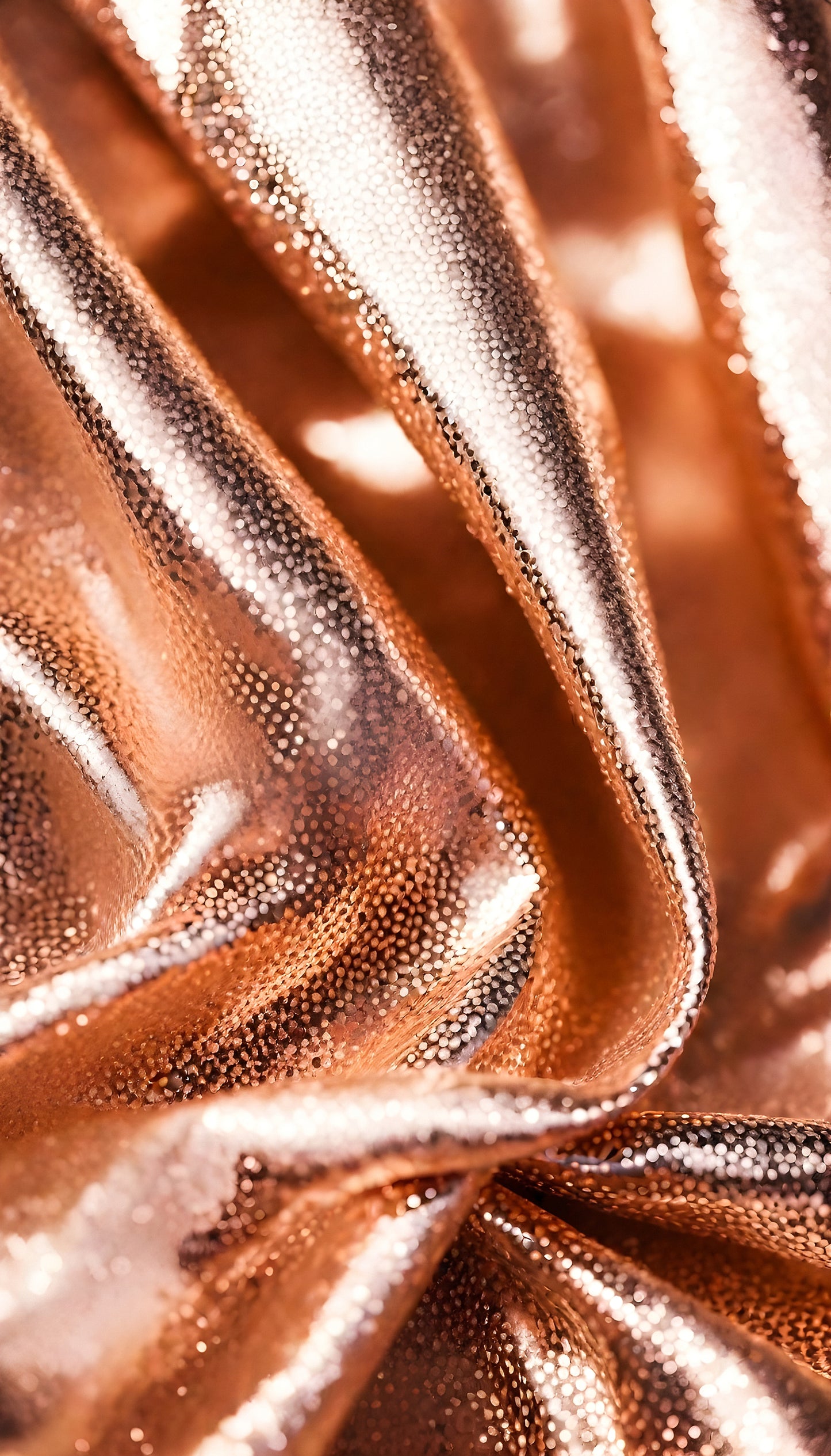 Soft draped copper metallic fabric with intricate textures under soft lighting