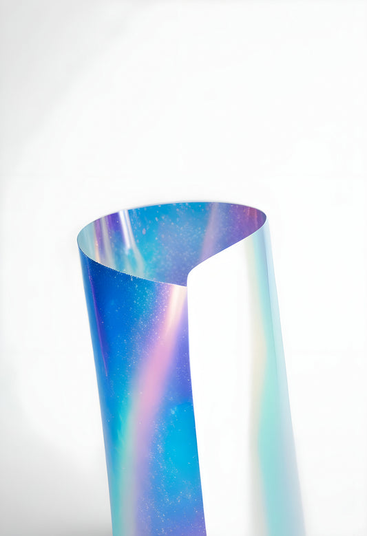 Colorful iridescent film curled into a heart shape against a plain light background