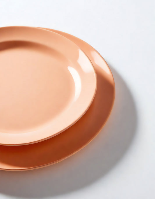 Simple peach-colored plates stacked on a clean surface, highlighting modern tableware design and minimalist aesthetics