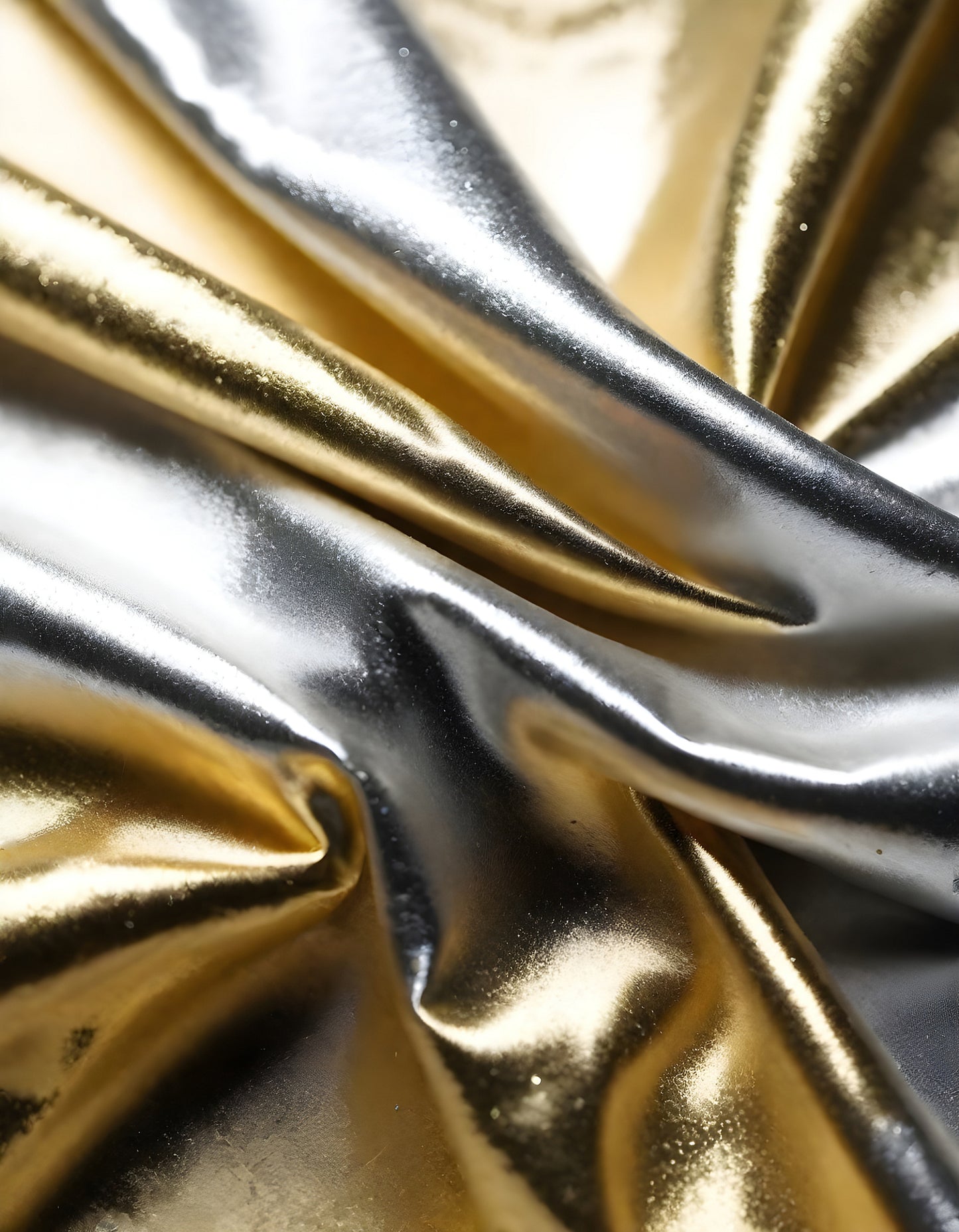 Metallic golden and silver fabric creates elegant textures with intricate folds and reflections under soft lighting