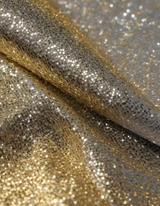 Metallic golden and silver fabric creates elegant textures with intricate folds and reflections under soft lighting