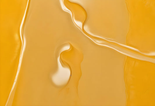 Golden honey flowing smoothly over a surface under soft light