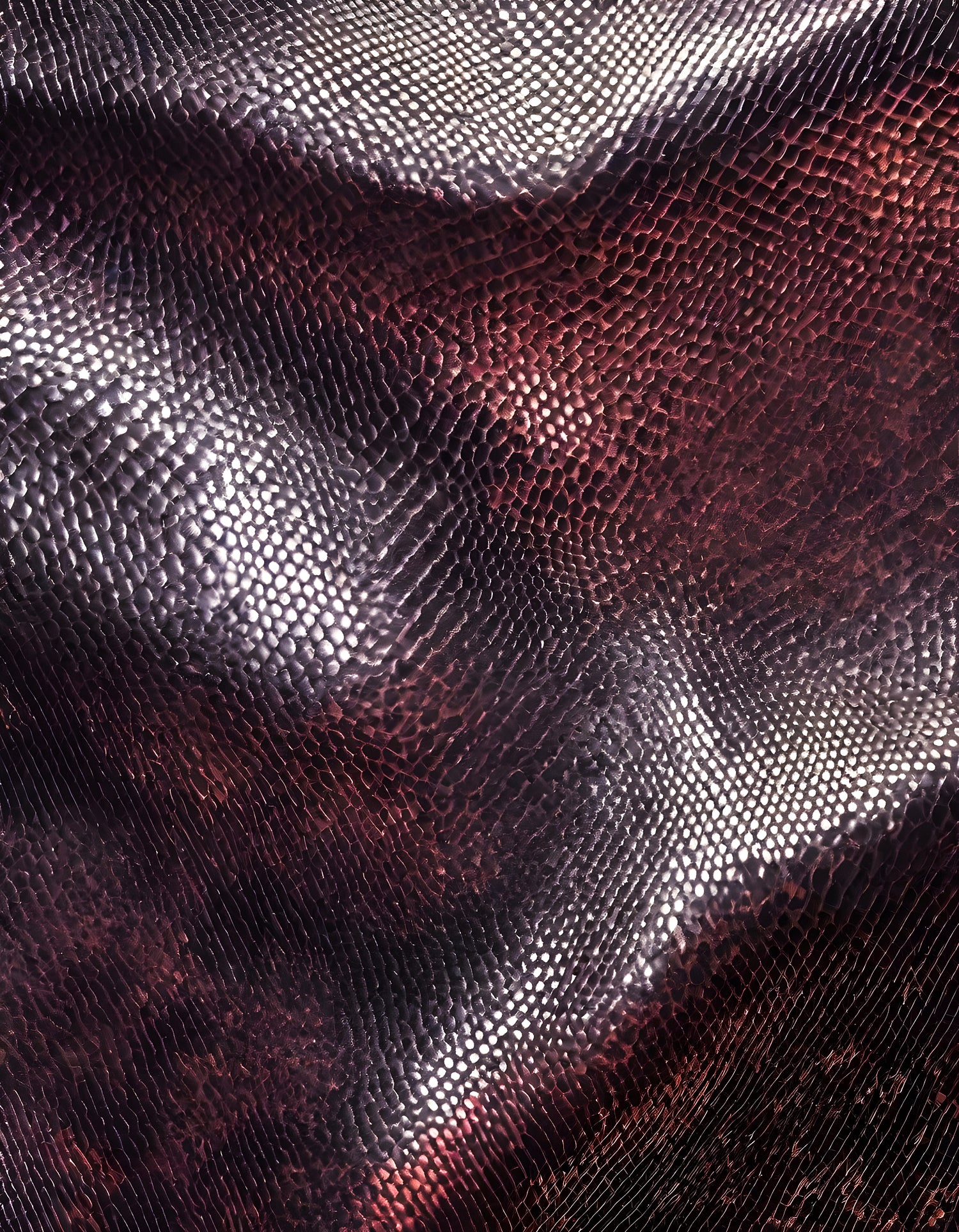 Textured surface of vibrant fabric in deep red and black tones illuminated by soft light