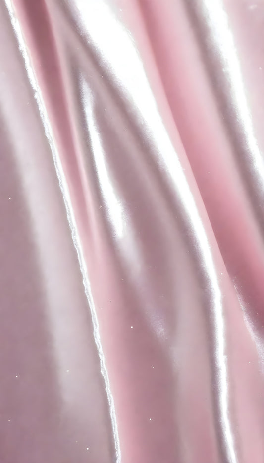 A close-up view of soft, shiny pink fabric draped elegantly, highlighting its smooth texture and sheen, perfect for luxurious designs