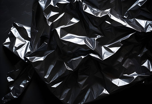 Crumpled black plastic sheet on a dark surface showcasing texture and light reflections