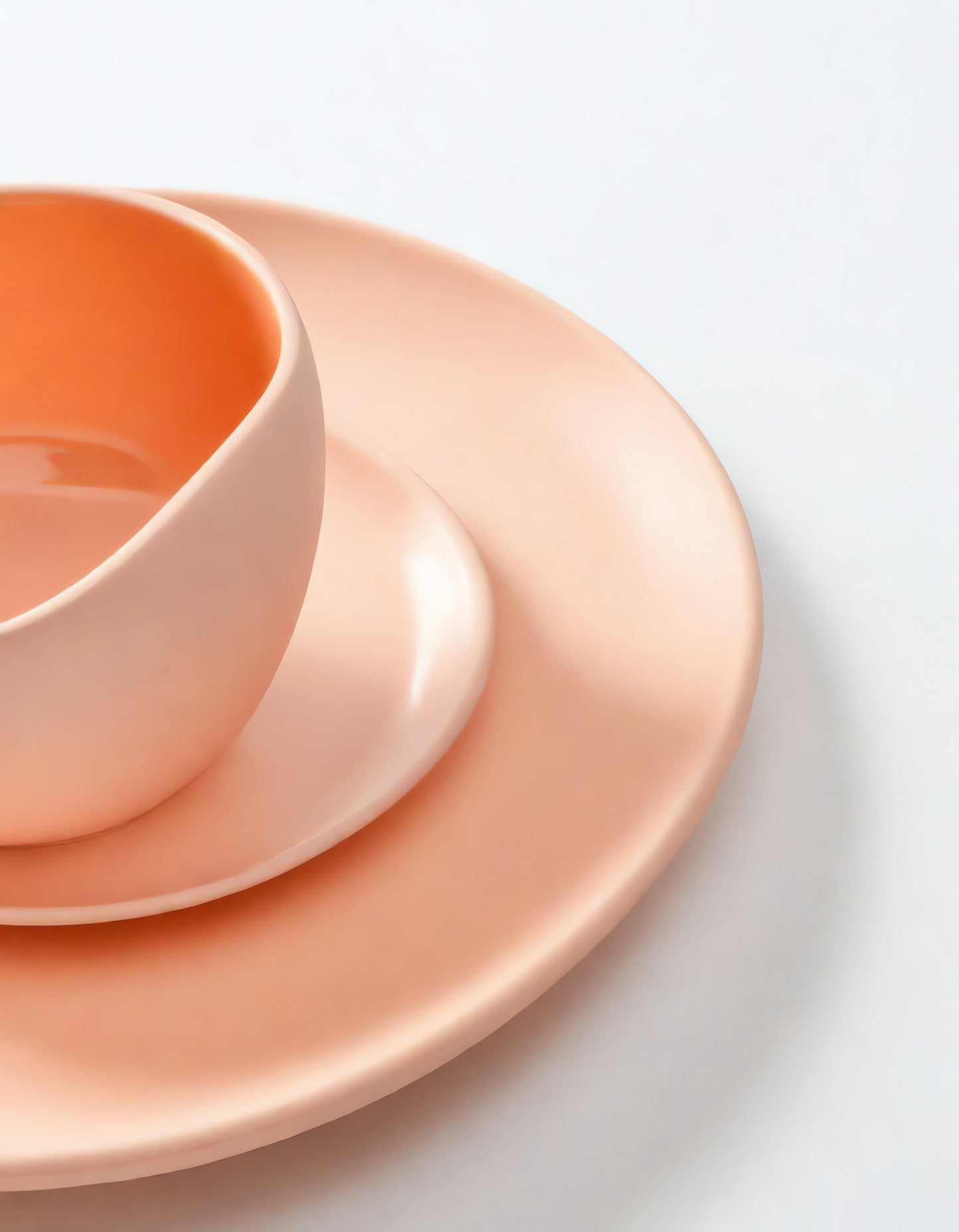 Elegant peach-colored dinnerware set arranged neatly on a clean table surface in a bright and inviting kitchen setting