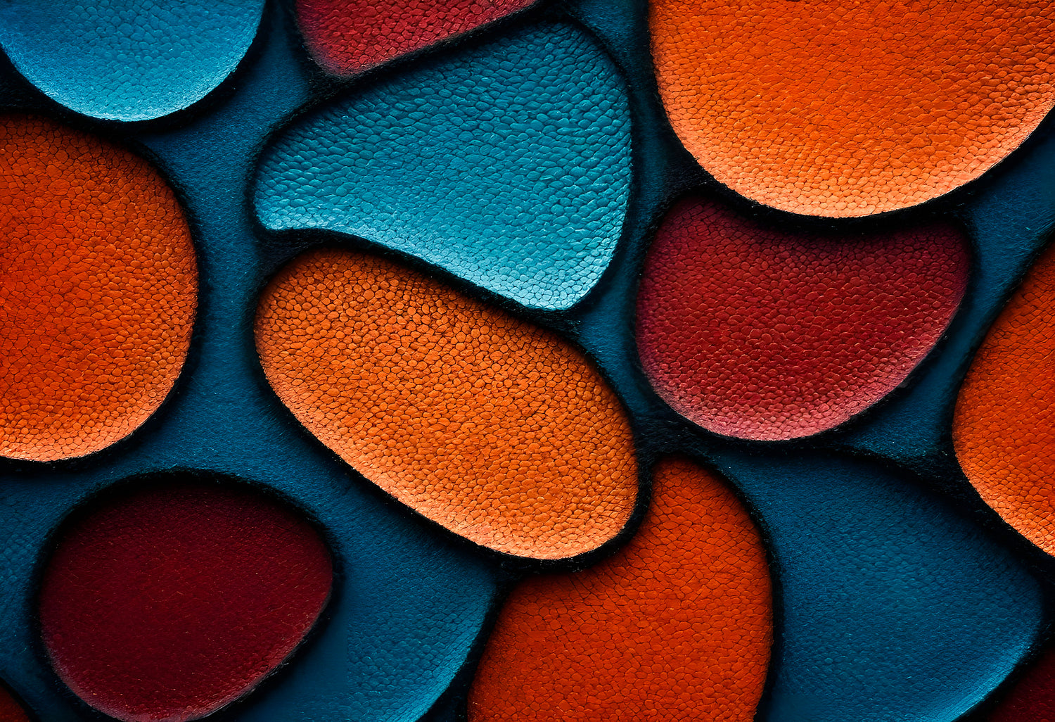 Colorful abstract shapes resembling pebbles arranged closely on a dark background