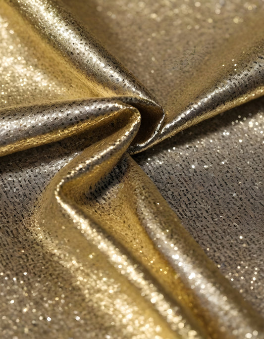 Shimmering gold and silver fabrics layered together in a luxurious arrangement during daylight