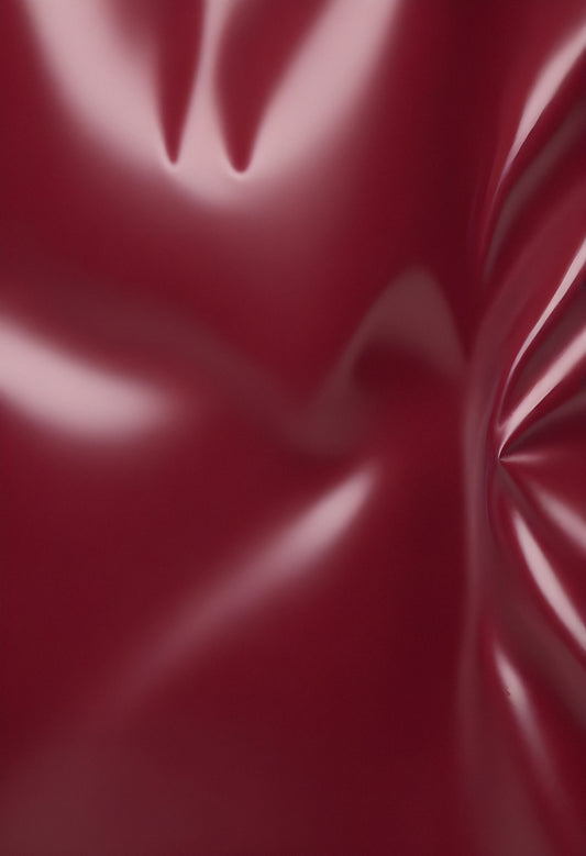 Deep maroon fabric draped elegantly on a surface, showcasing smooth texture and subtle shine in soft lighting