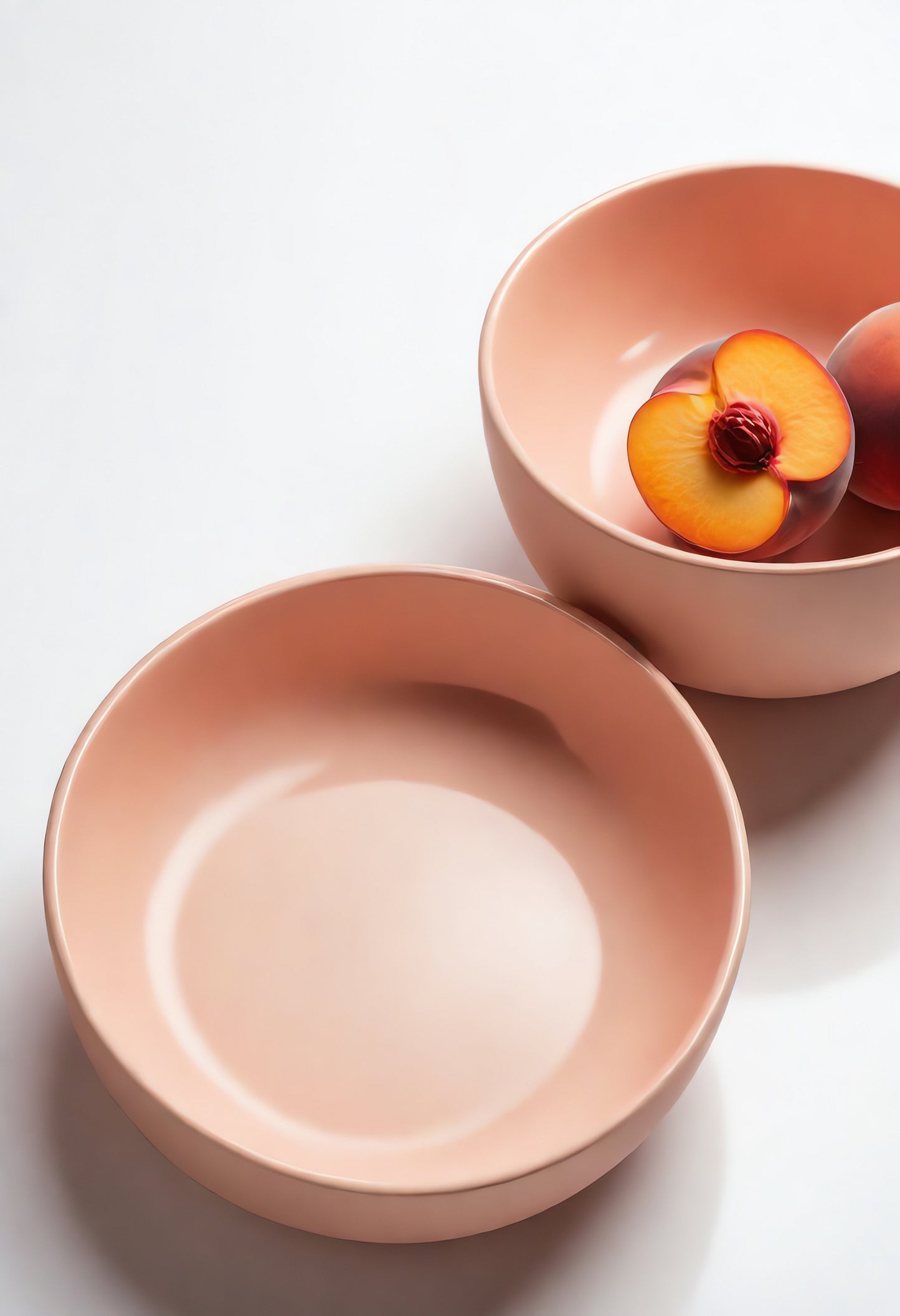 Delicate peach-colored bowls with a sliced fruit garnish, showcasing minimalist design at a bright kitchen table