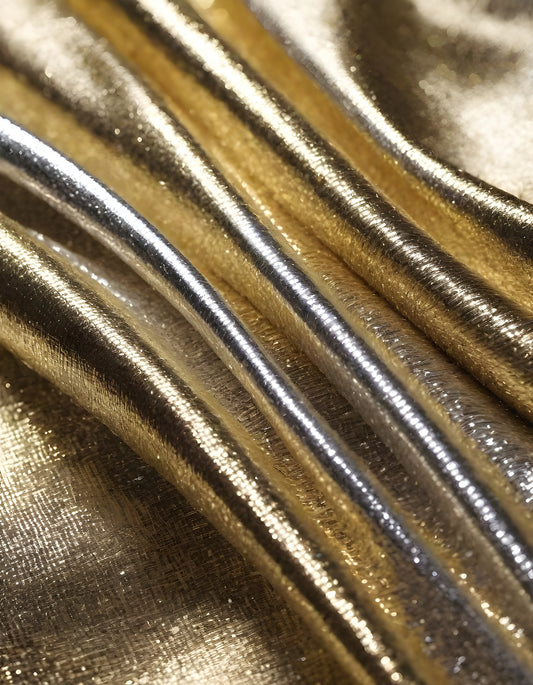 Metallic golden and silver fabric creates elegant textures with intricate folds and reflections under soft lighting