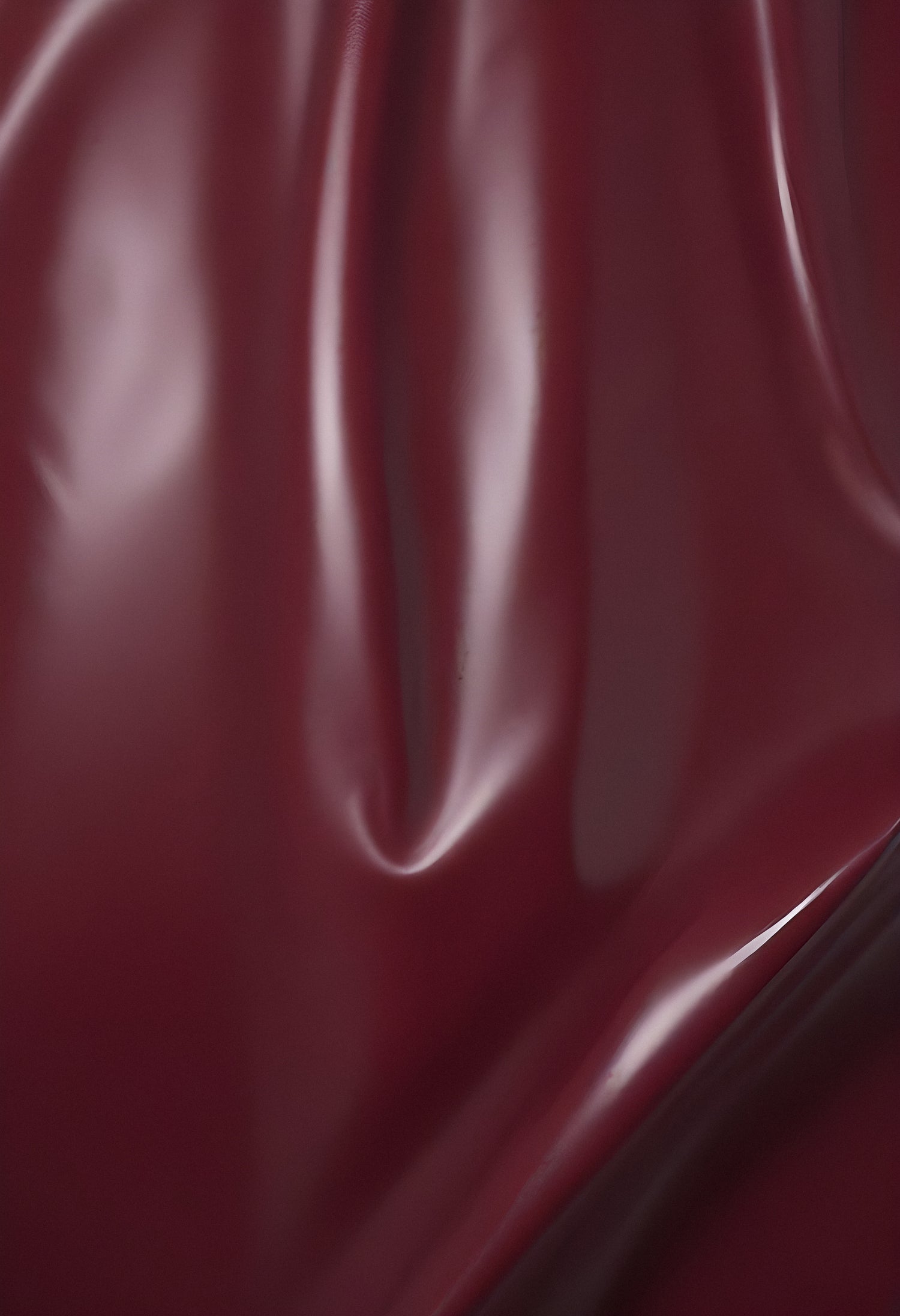 Deep maroon fabric draped elegantly on a surface, showcasing smooth texture and subtle shine in soft lighting