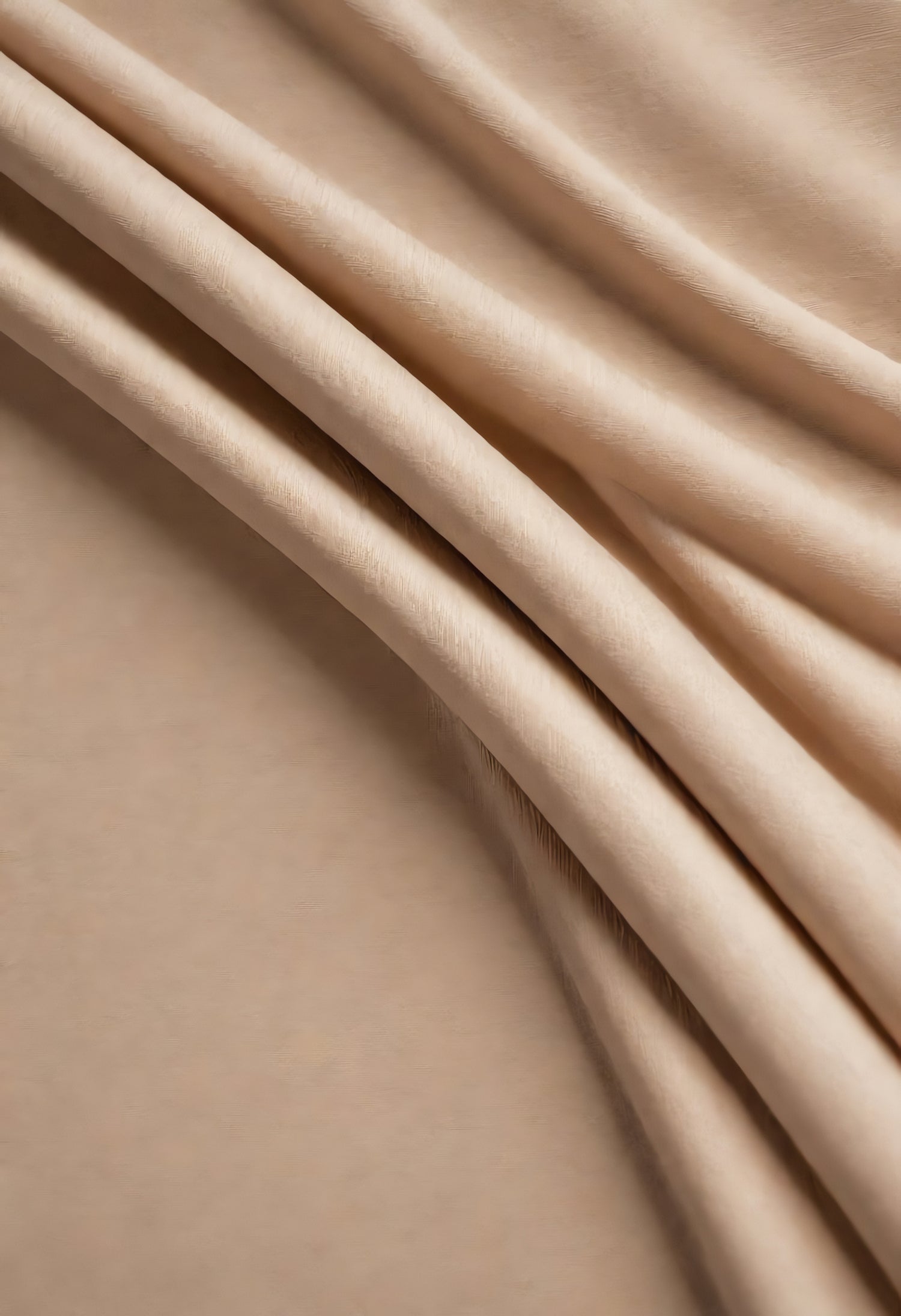 Soft, textured fabric draping elegantly against a neutral background in warm, muted tones