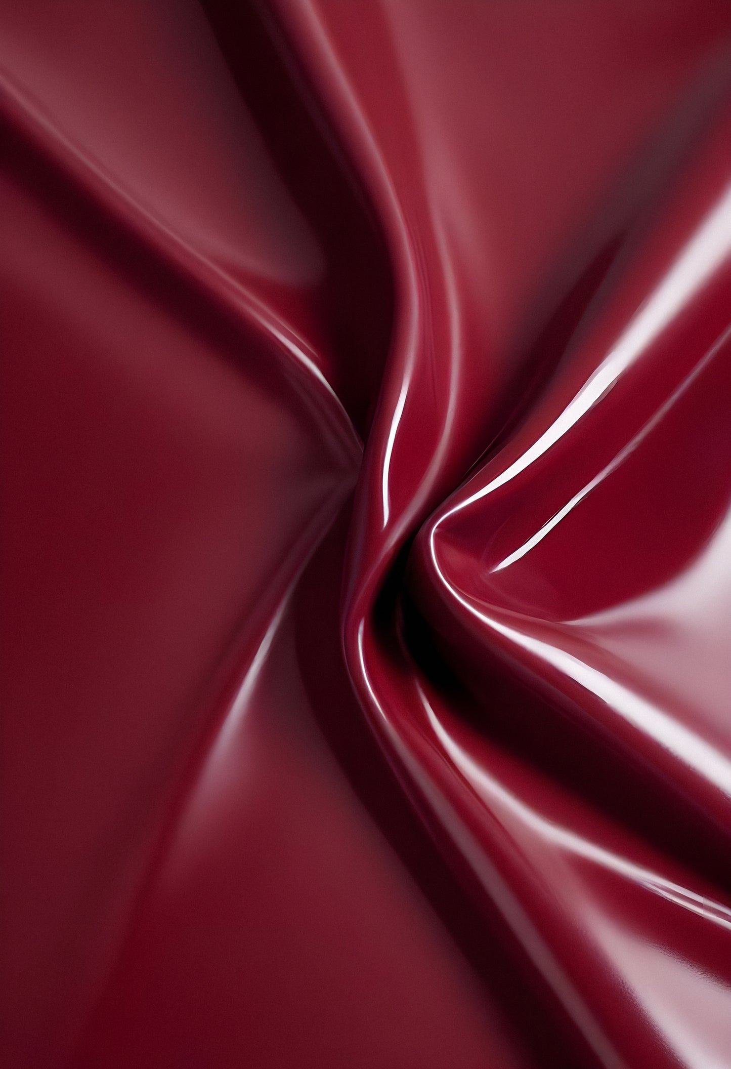 A close-up of deep red glossy leather fabric with soft, flowing folds illuminated by gentle light