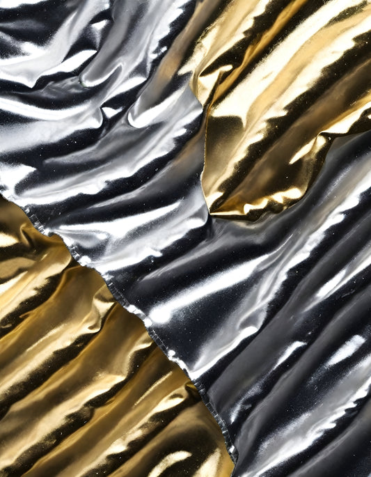 Textured metallic fabric in silver and gold hues displayed on a flat surface, showcasing elegant folds and reflections