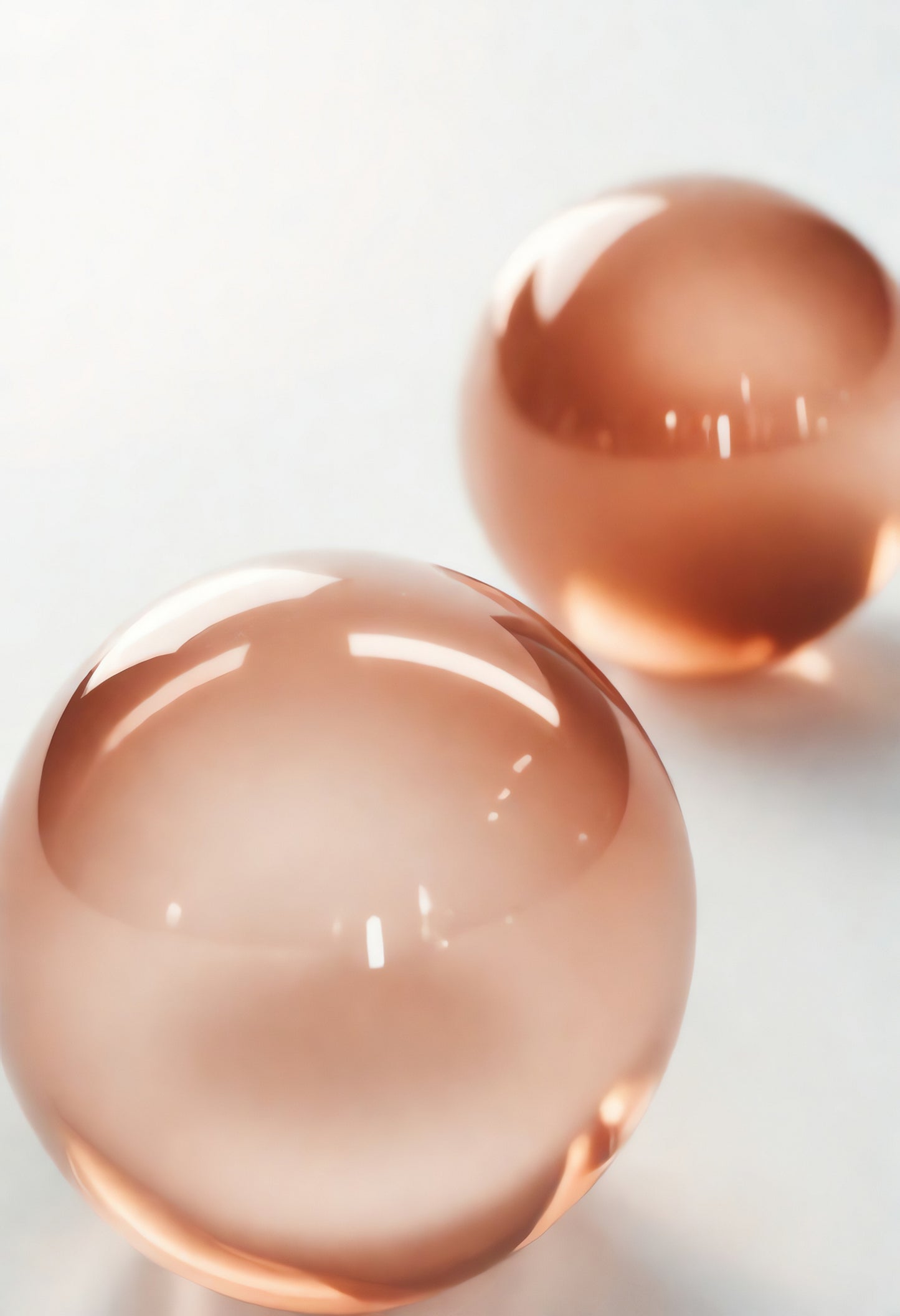 Translucent pink water beads resting on a smooth white surface, showcasing their glossy textures and reflections in natural light