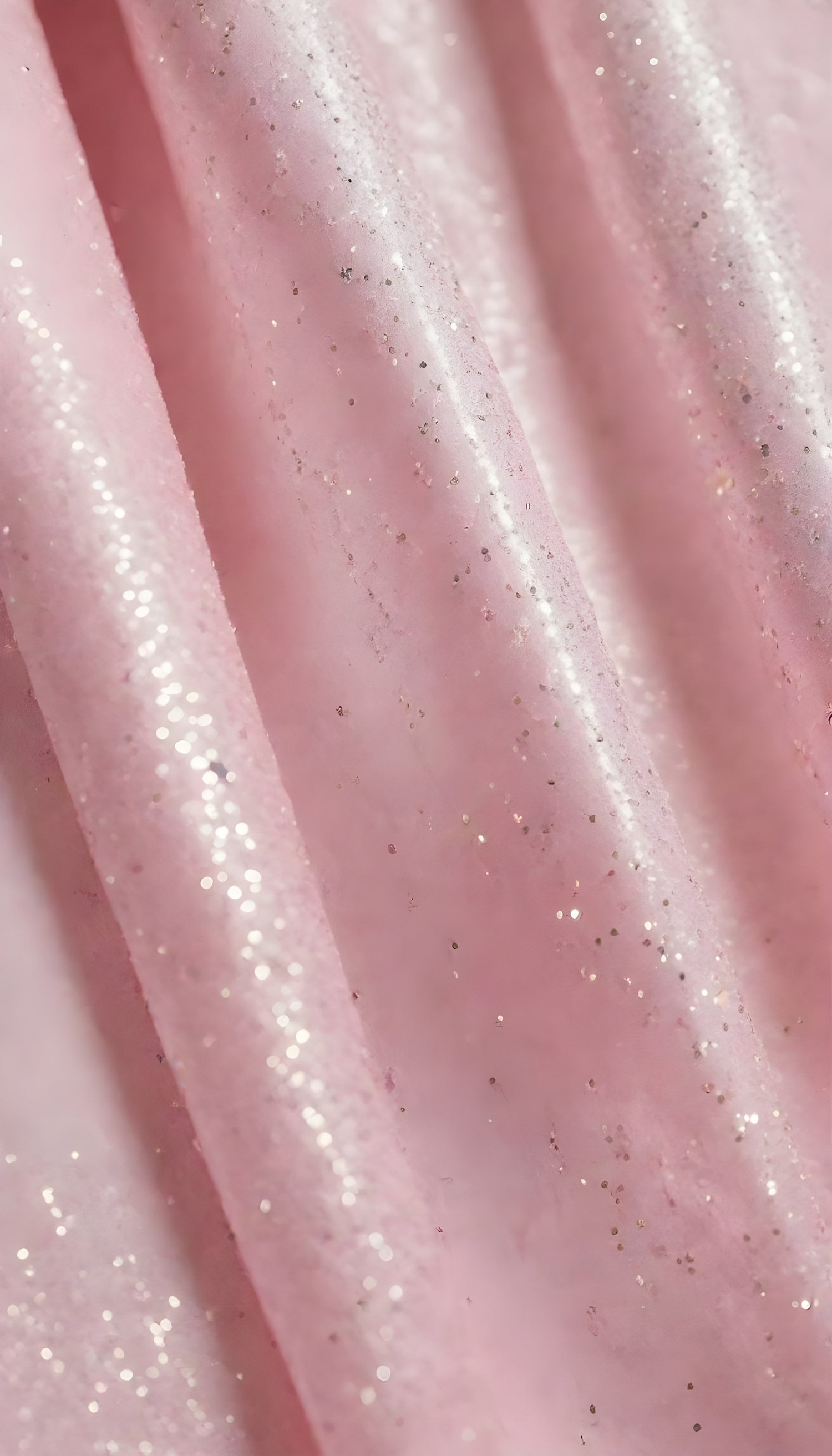 A close-up view of soft, shiny pink fabric draped elegantly, highlighting its smooth texture and sheen, perfect for luxurious designs