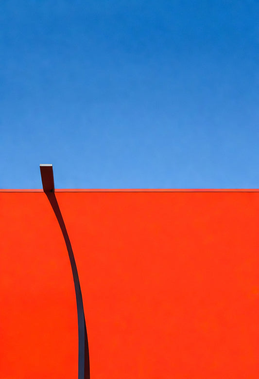 Vivid red wall contrast against bright blue sky highlighting simplicity and modern architecture in a minimalist setting