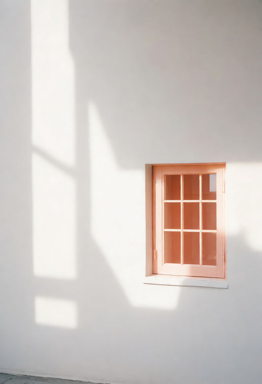 Light patterns cast by a peach-colored window on a white wall in a serene indoor setting during daylight hours