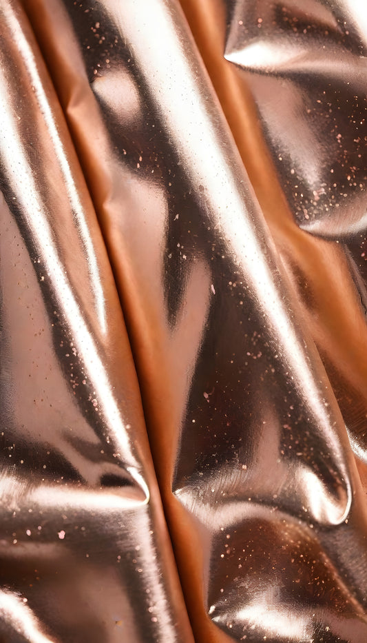 Shimmering rose gold fabric draping elegantly with soft folds under bright light in a studio setting