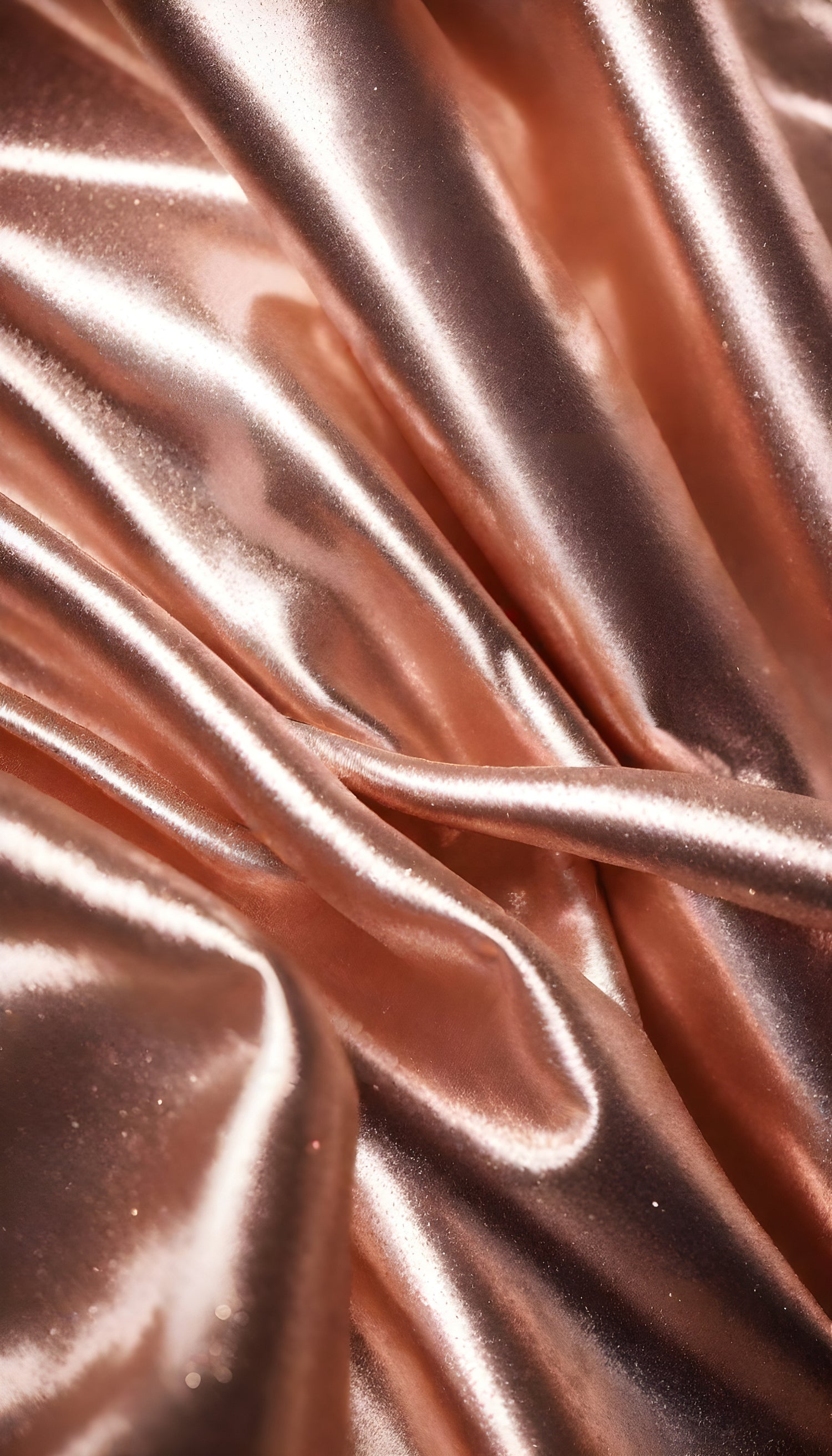 Shimmering rose gold fabric draping elegantly with soft folds under bright light in a studio setting