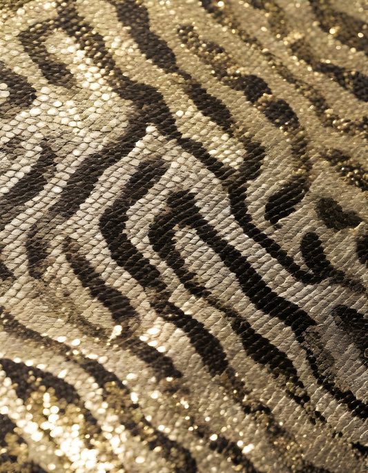 Shimmering gold and black patterned fabric with a textured zebra stripe design